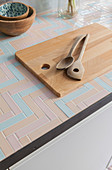 Salad servers and wooden chopping board on kitchen worksurface