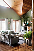 Wohnzimmer in Naturtönen mit hoher Decke und grünen Wänden