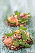 Wholegrain bread topped with avocado slices, salmon and rocket
