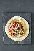 A tortilla wrap with pulled pork, hummus and coleslaw