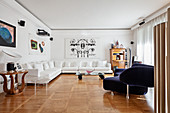 White corner sofa, blue designer sofa and artworks in elegant interior