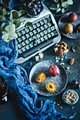 Pflaumen, Trauben und Nüsse vor alter Schreibmaschine