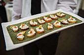 Waiter serving hors d'oeuvres of toast with cheese and herbs at an event