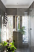 Houseplants in full-width shower with glass-brick wall