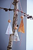 Paper and bead angels hung from branches on baker's twine