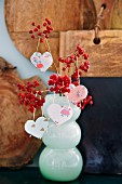 Patterned paper heart pendants hung from branches of berries