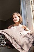 Woman beating pillows at the window