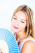 Woman cooling her face with a fan