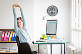 Office woman stretching arms at work