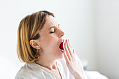 Tired woman using her hand to cover a yawn