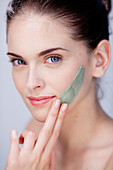 Woman applying green clay cosmetic beauty mask