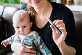 Woman smoking electronic cigarette beside a baby