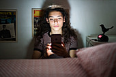 Teenage girl using a smartphone at night