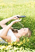 Woman lying on grass with cell phone