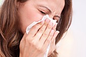 Woman blowing nose on tissue