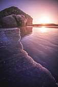 Sunset at water's edge on beach