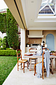 Wooden table and chairs on covered terrace with gas grill