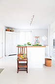 Basket on chair in front of white kitchen island in front of white corner cabinet