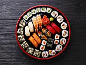 Sushi Set nigiri and rolls served in traditional Japan black Sushioke round plate