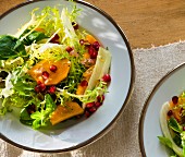 A mixed leaf salad with mango and pomegranate seeds
