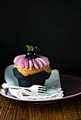 A cupcake decorated with blackcurrants
