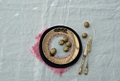 Gold-painted walnuts on gold-rimmed plate and silver cutlery