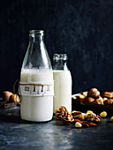 Homemade nut milk in two bottles, nuts next to it