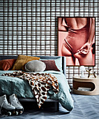 Double bed against wall with wallpaper and large-format photo, next to it round bedside table
