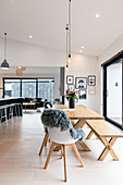 Wooden table with bench and chairs in the open living room with high ceiling