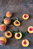 Peaches and peach halves on a metal surface