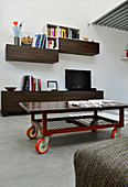Coffee table on castors, TV on sideboard and wall-mounted shelves in industrial loft apartment