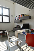 Designer chairs, TV on sideboard and wall-mounted shelves in dining area of industrial loft apartment