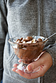 A woman holding a bowl of chocolate pudding topped with chocolate covered cookies