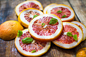 Pink grapefruit slices with mint leaves on a wooden background