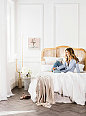 Young woman on double bed in front of white cassette paneling in bedroom