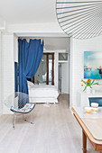 Klassikerstuhl vor Schlafbereich mit blauem Vorhang