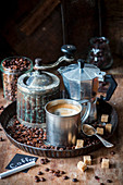 An arrangement of coffee with an espresso jug, a coffee mill, sugar and coffee beans