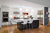 White fitted kitchen and island counter with barstools