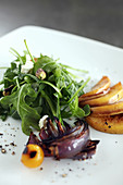Arugula salad with grilled peach, grilled red onion, feta and pistachios