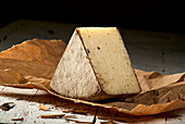 A wedge of pecorino with potash and cinnamon on paper