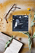 Black-and-white photo in hand-made frame, dried flowers, note book and spectacles