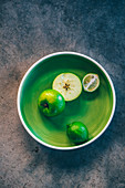 Half a green apple and limes in a green bowl
