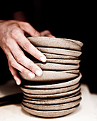 Hands stacking ceramic plates