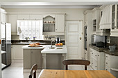 L-shaped counter in renovated country-house-style kitchen with dining area in foreground