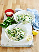 Two bowls of lemon risotto with spinach leaves