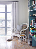 Rattan armchairs and stools next to blue bookshelf