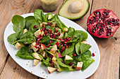 A superfood salad with baby spinach, avocado, apple, quinoa and pomegranate seeds