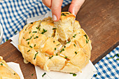 Pull-apart bread with chives and a hand taking a piece