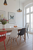 Various designer chairs around dining table next to period window