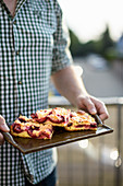 A man holding a tray of plum cake